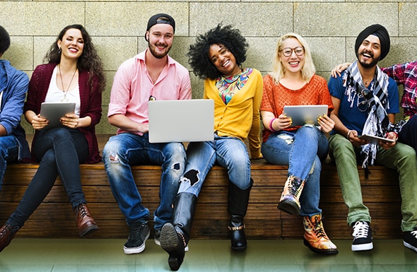 Young adults sitting together using laptops and tablets, casual setting