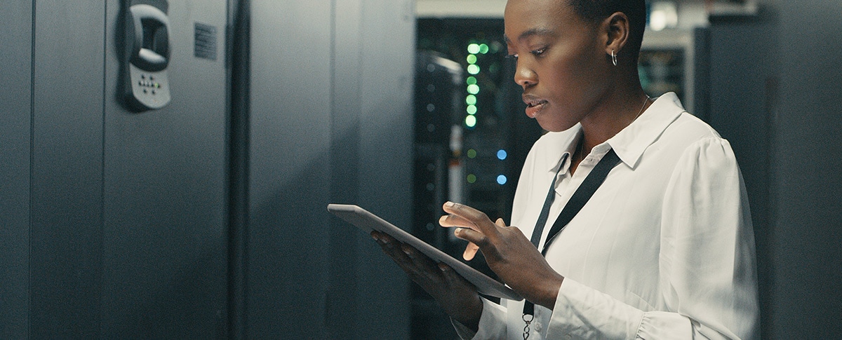 Woman engineer using a tablet in a server room with equipment.