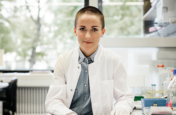 Woman scientist in a laboratory wearing a white coat with equipment around.