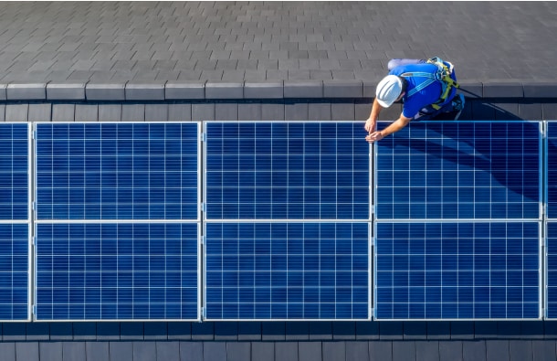 Aerial view of a man installing a solar panel on a roof