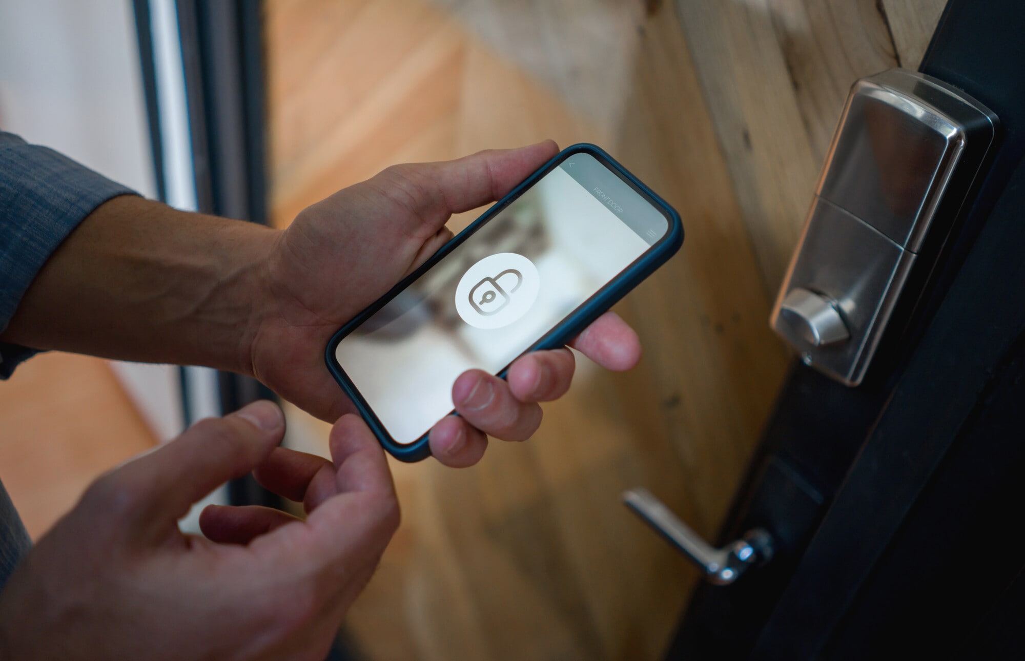 Close-up on a man opening the door of his house using a home automation system on his cell phone