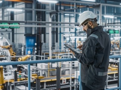 worker checking parameters of complex production system on tablet